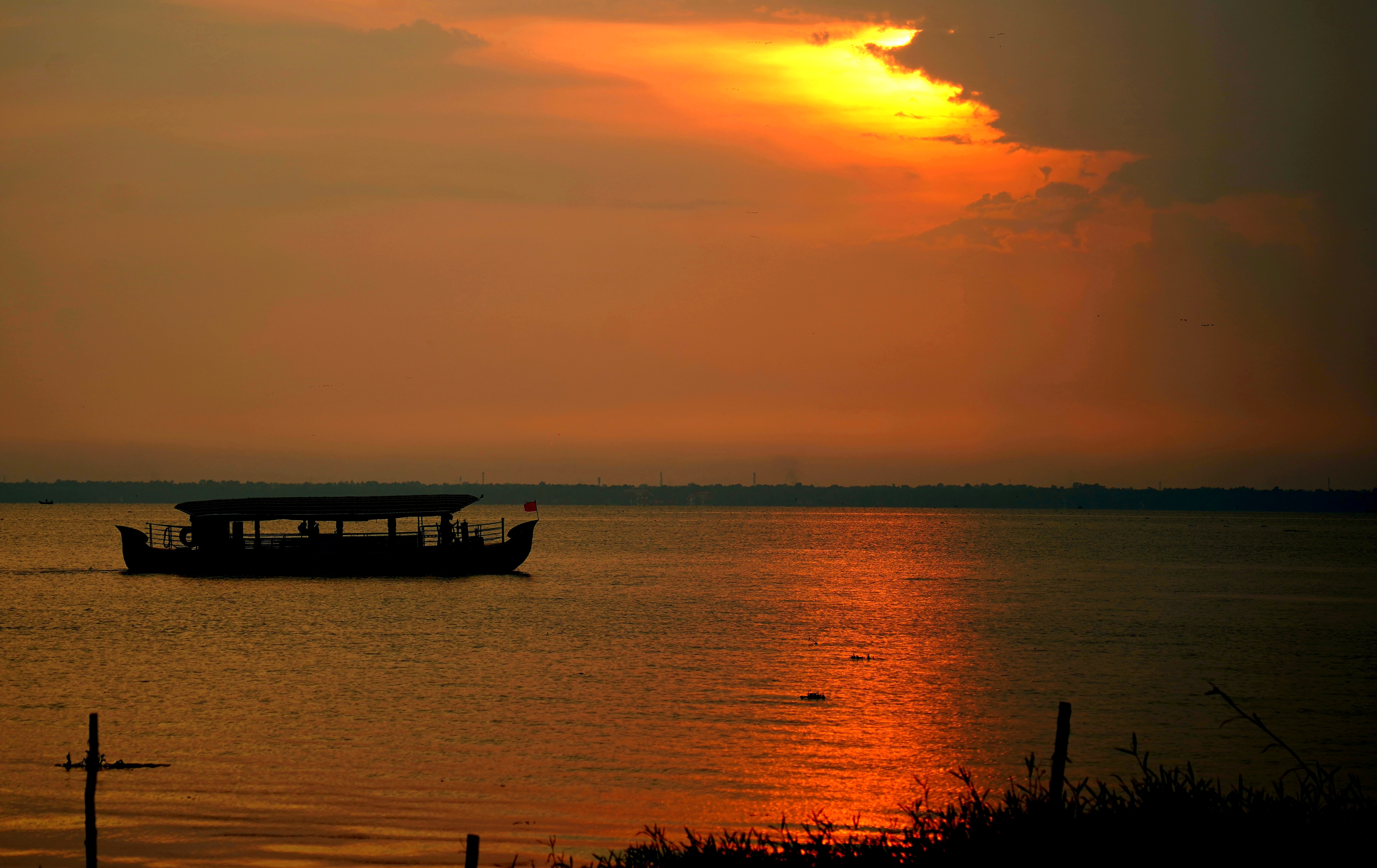 Boat silhouetted on calm water at sunset